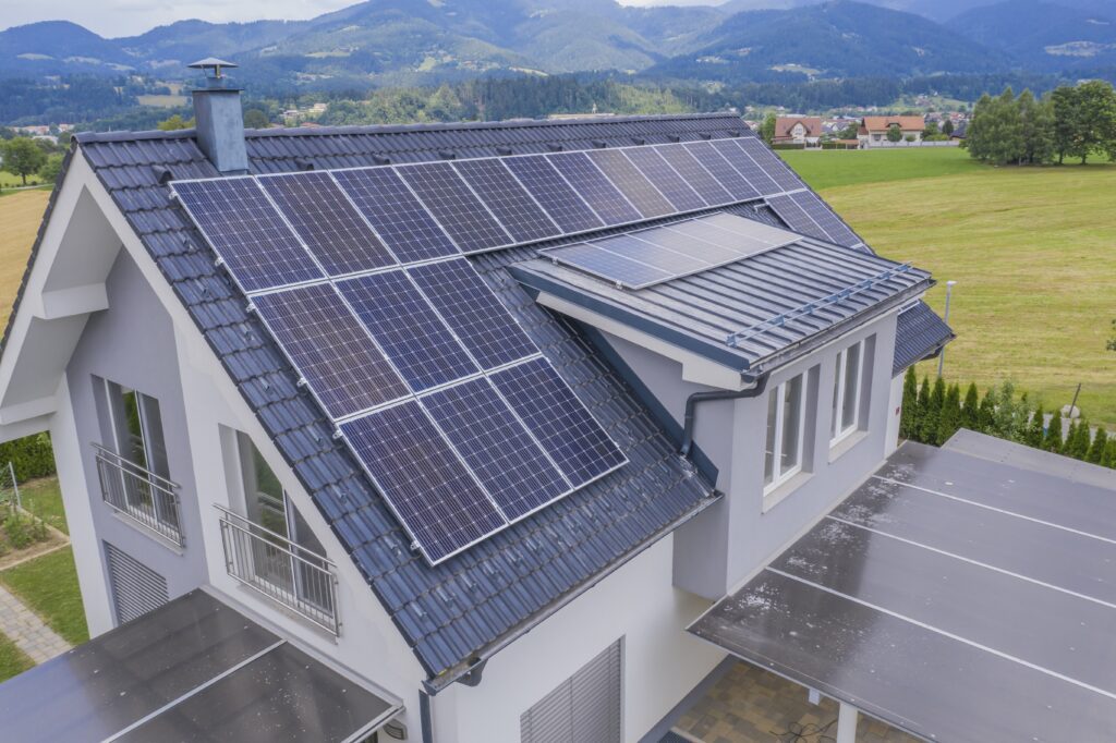 Toma desde un ángulo alto de una casa particular situada en un valle con paneles solares en el tejado.